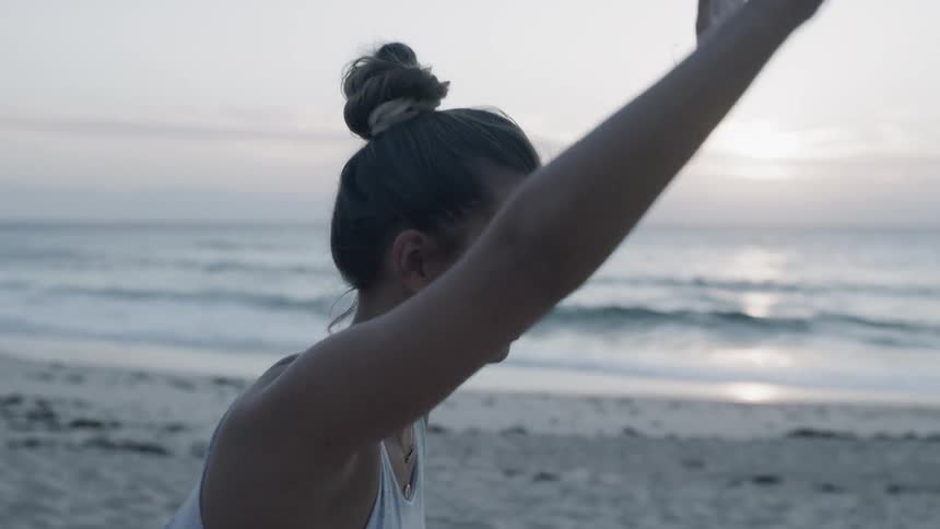 Woman does yoga on a beach at sunset