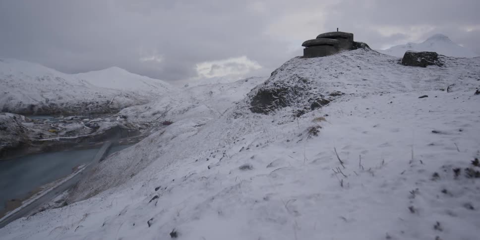 An observatory sits on a snowy hilltop overlooking a road and water below