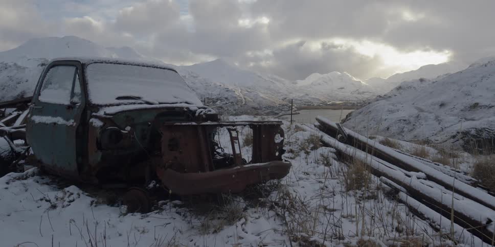 An old broken truck is covered in snow