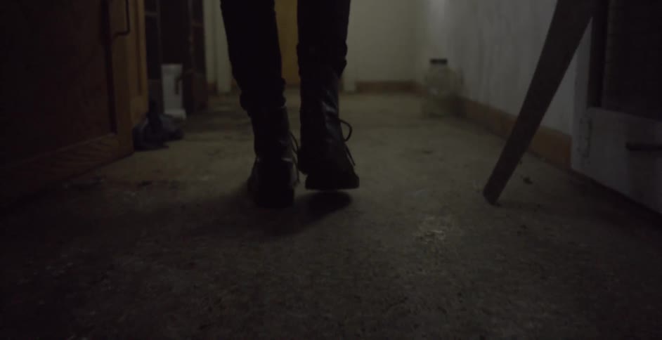 A person walks through the hallway of an abandoned building