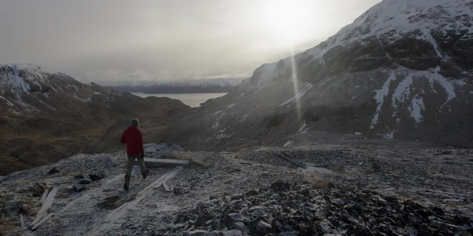 A man runs towards the cliff as the sun shines