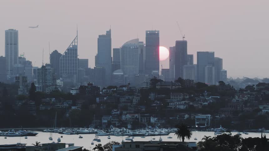 The sun sets behind skyscrapers