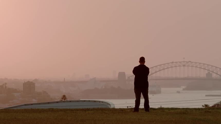 Man overlooks a river and city buildings at sunset
