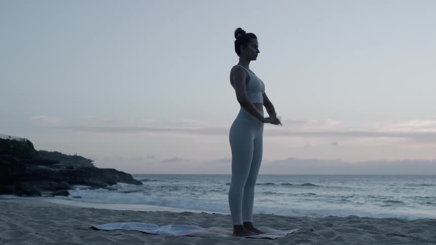 A woman stretches on the beach