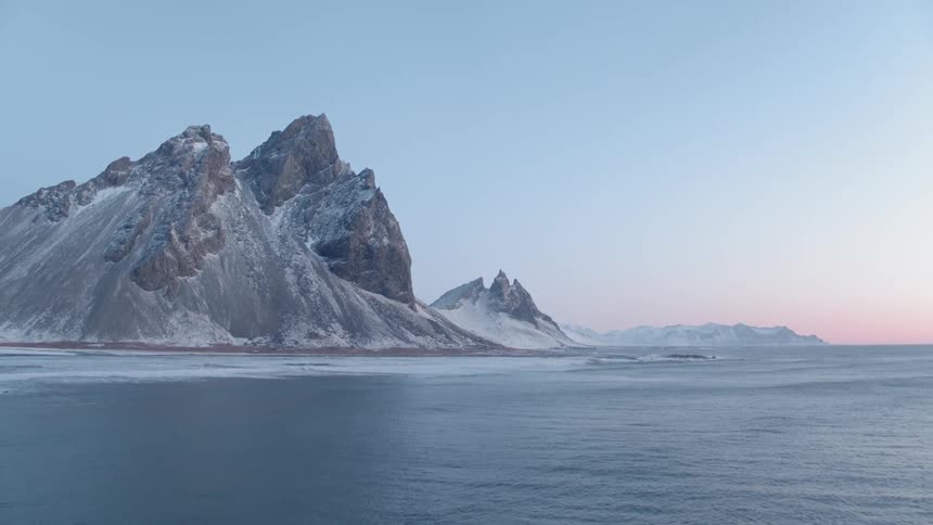 Water flows on an icy mountain lake at sunset