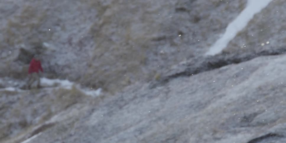 A person walks over a mountain on a snowy day