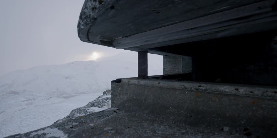 Snow falls around a concrete structure in mountains