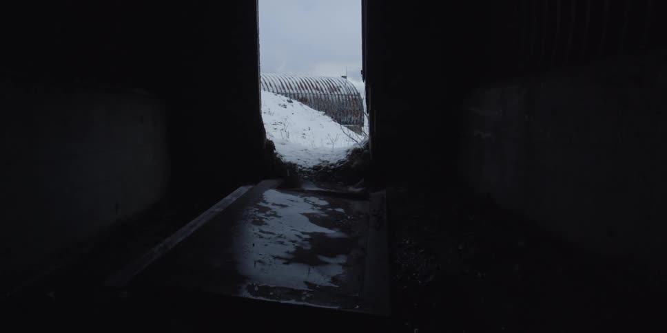 Snow covers the ground outside an abandoned building