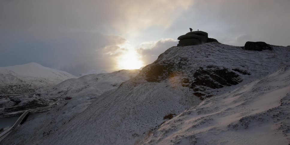 Someone is standing on top of a bunker at the top of a snow covered hill