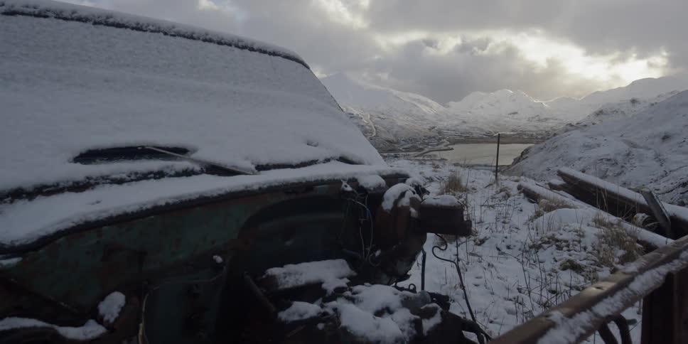 Snow covers a rusted out truck in the snow
