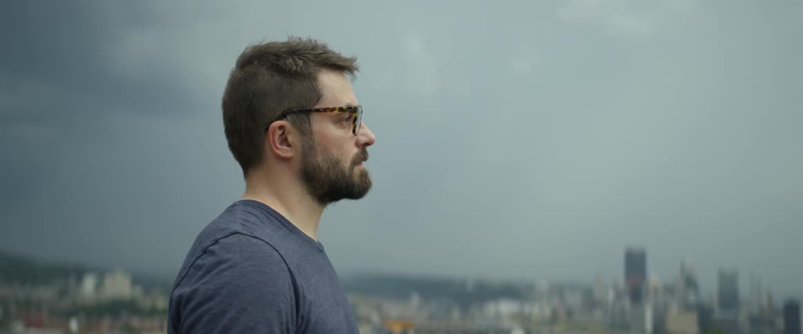 A man overlooks a city on a cloudy day