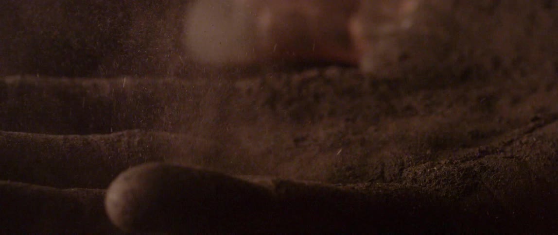 Dirt sifting on the ground and billowing up into smoke