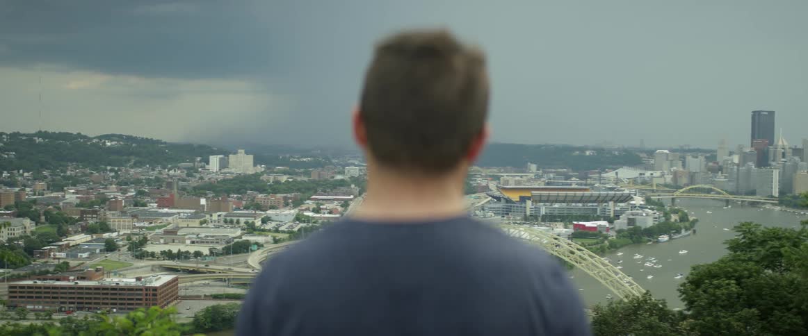 A man overlooks a city during a lightning storm