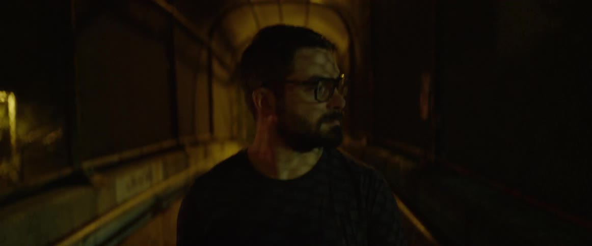 A man is walking down a dark tunnel at night