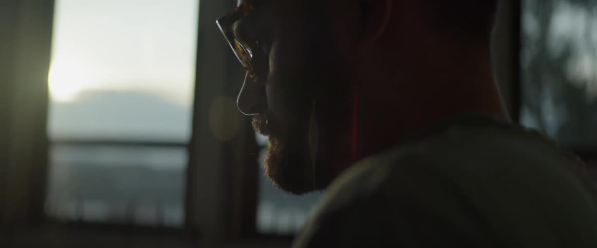 A man sits next to a window at sunset