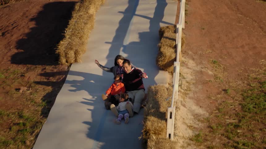 A family of four is sliding down a slide together
