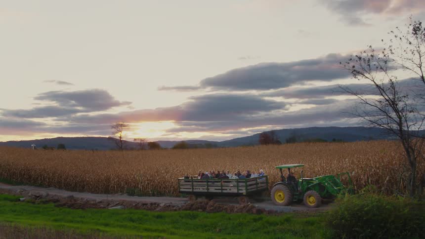 People go on a hay ride on a farm at sunset