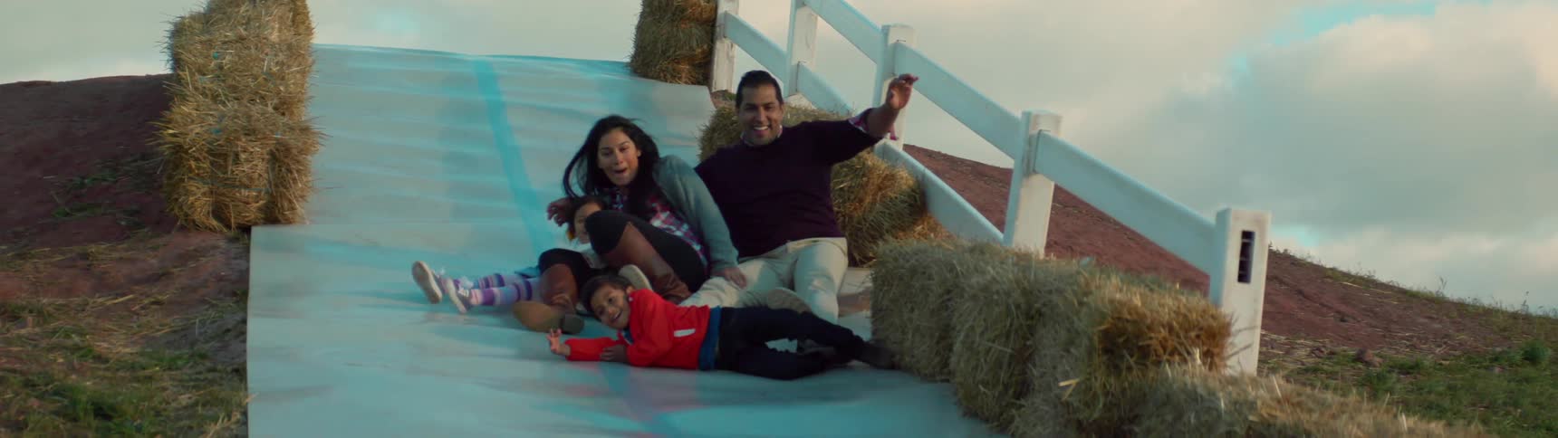 A family slides down a hill on a farm