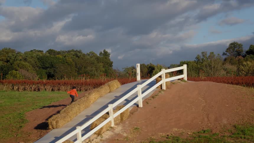 A boy runs up a hill on a farm