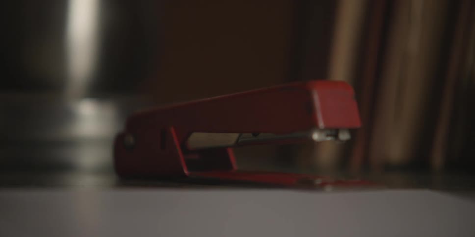 A single red stapler sits motionless on a desktop