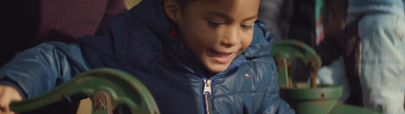 A boy smiles as he works the handle of a pump