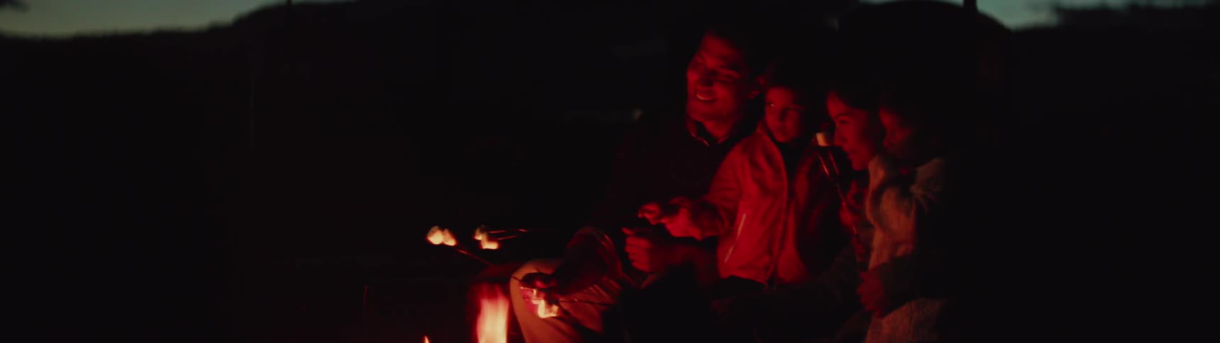 A family roasts marshmallows over a campfire