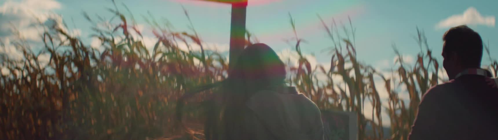 A family is walking towards a sign that says corn maze starts here