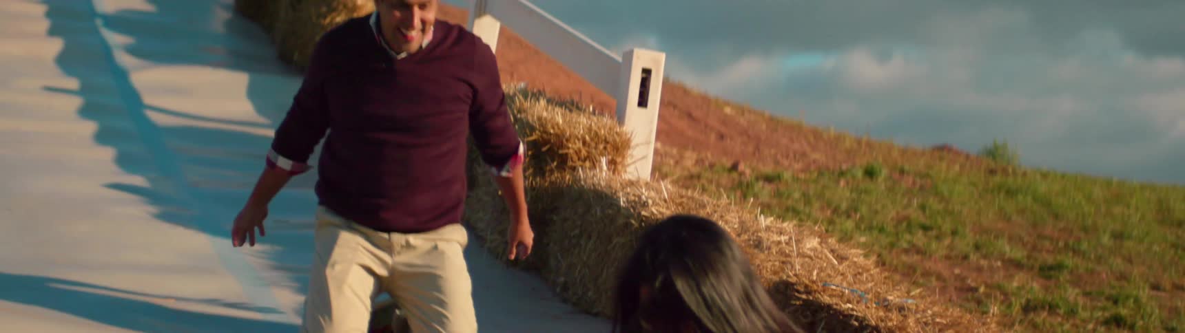 A family is sliding down a slide in the middle of a field