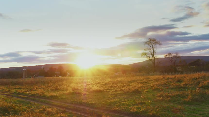 The sun sets over a rural field