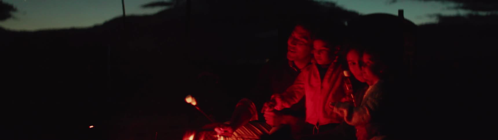 A family roasts marshmallows over a campfire