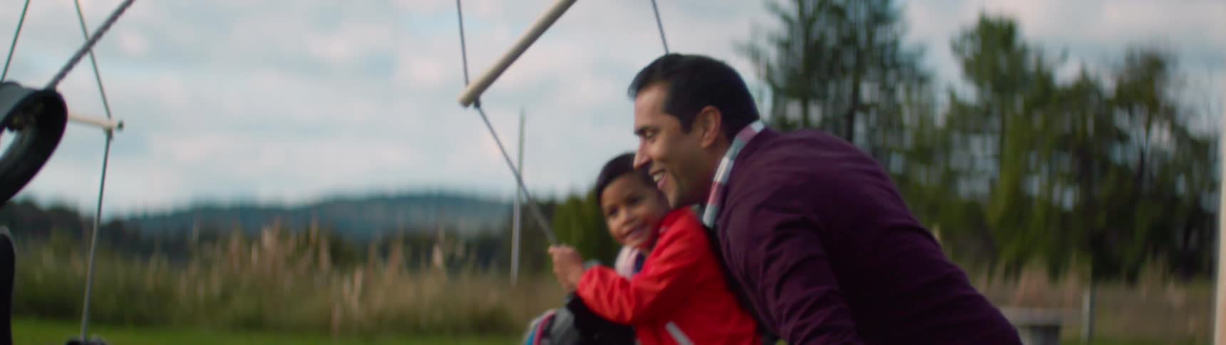 A man pushes children on swings
