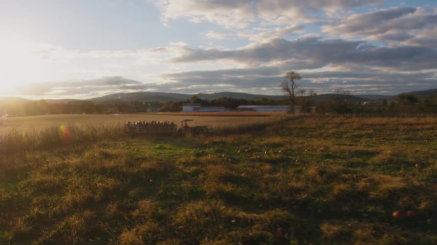 A tractor is carrying a group of people through an open field