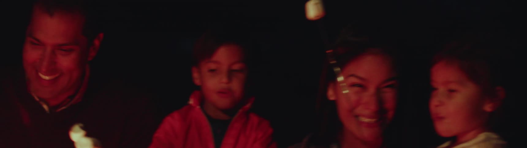 A family roasts marshmallows around a campfire