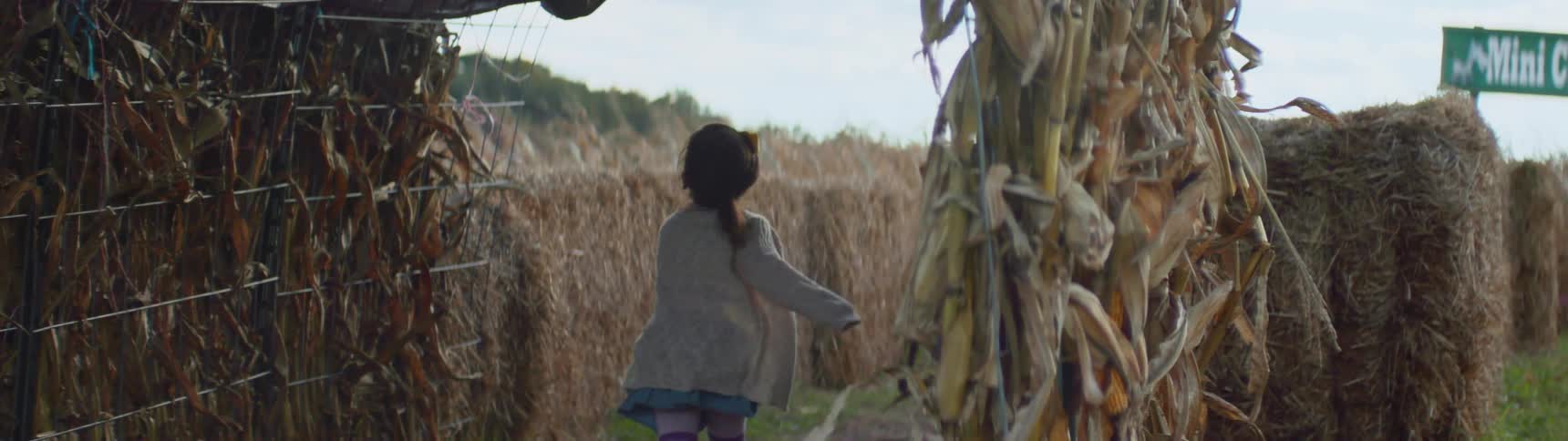 Children run past corn stalks and hay bales