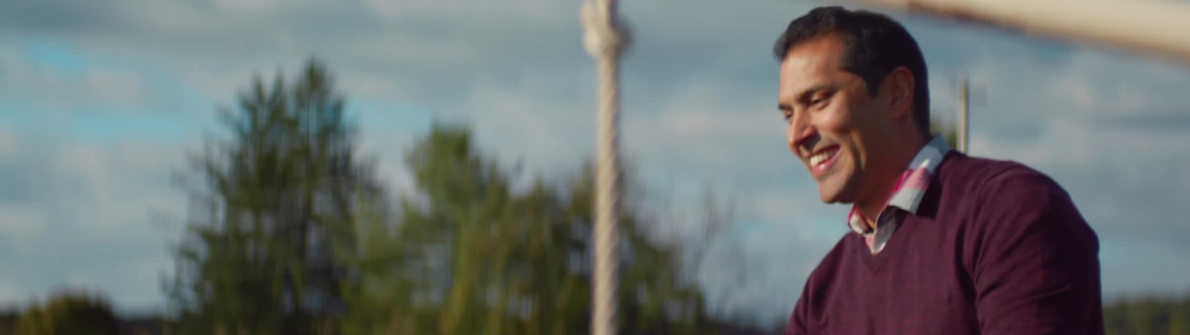 A man is swinging his kids on a swing and smiling