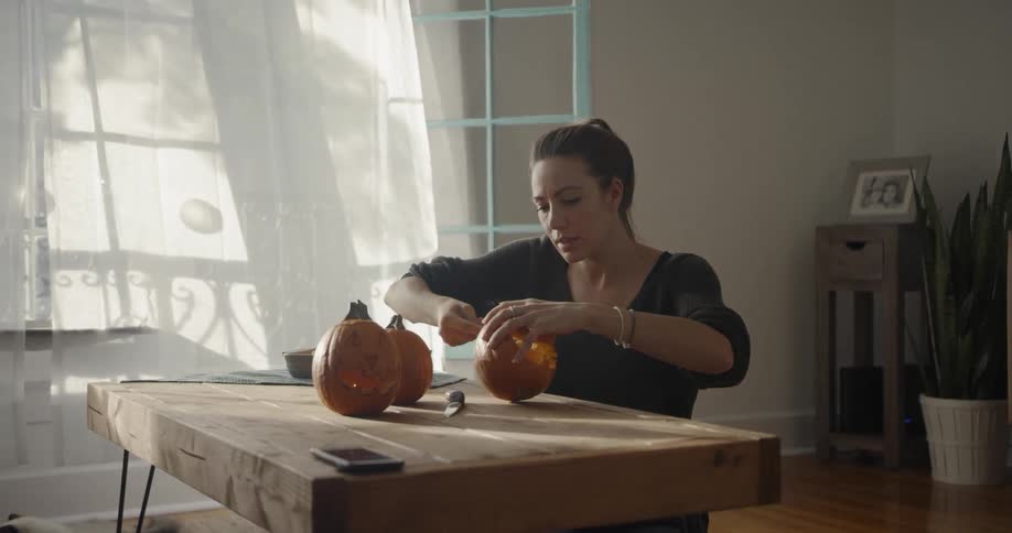 A woman scooping out pumpkin innards