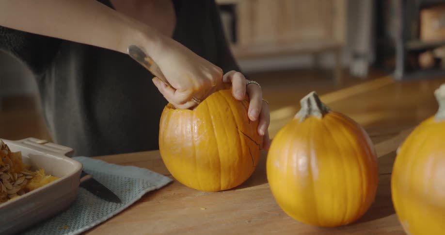 A woman is hollowing out a pumpkin