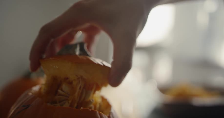 A person removes the top of a pumpkin