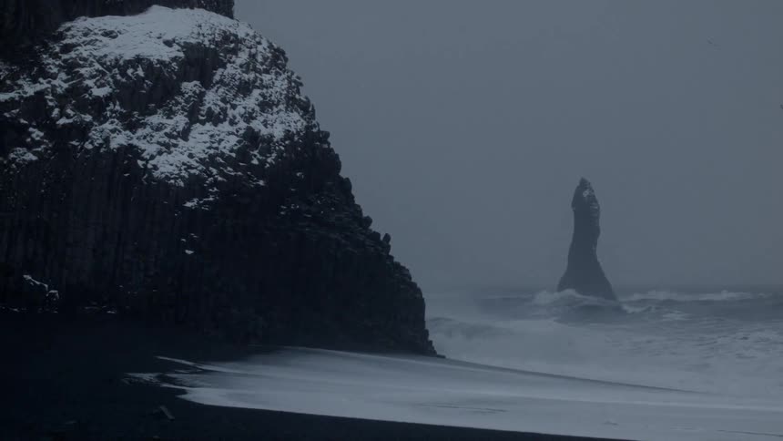 Ocean waves crash against the rocks on shore on a winter day