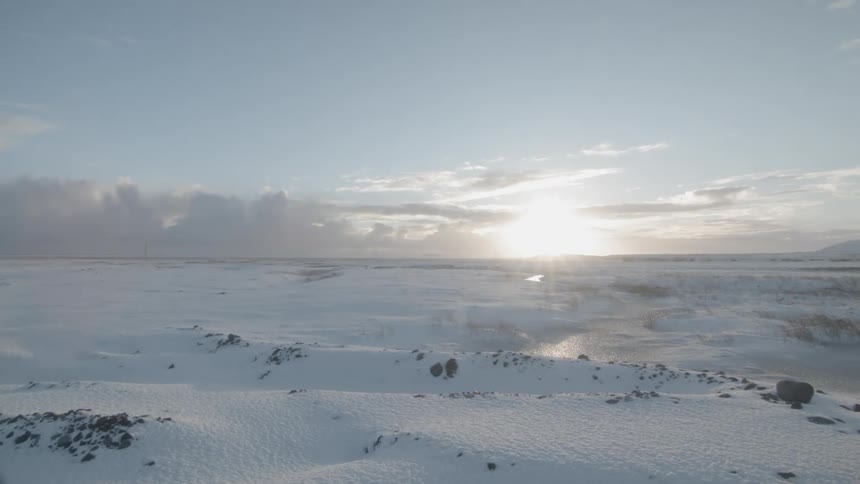 The sun shines on snow covered rocky terrain