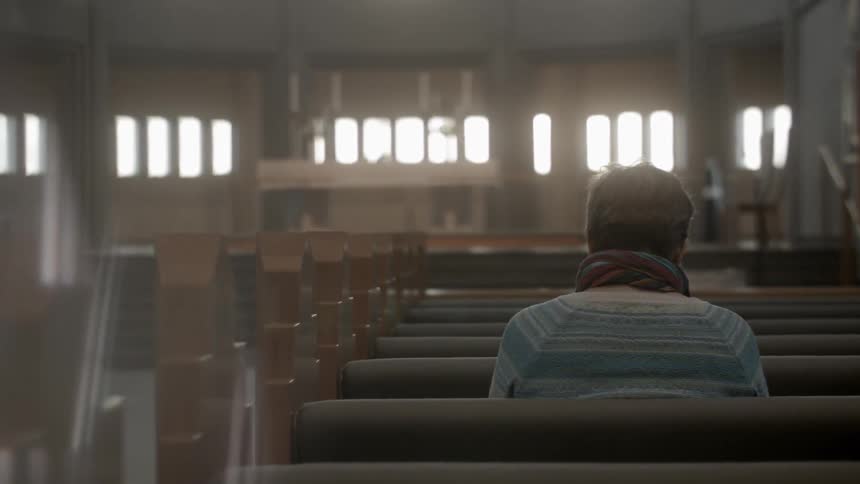 A woman sits alone in a church