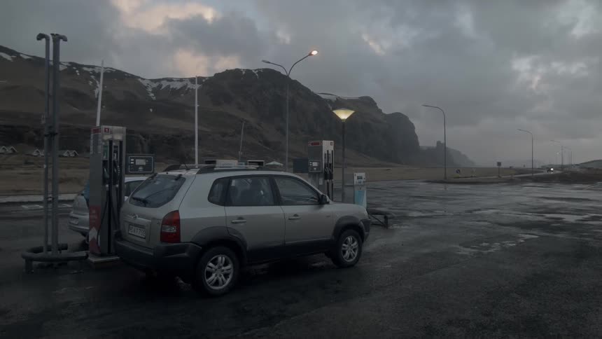 A car is at a gas pump on a cloudy wet day