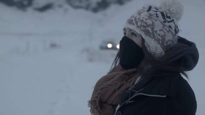 A woman stands outside in the snow