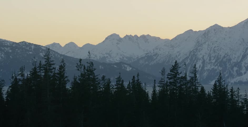 Dawn is breaking over snow-covered mountain peaks