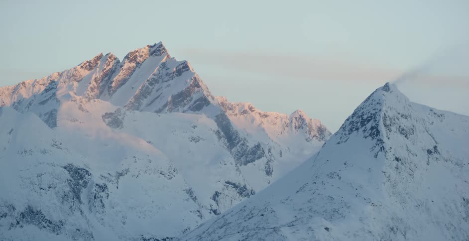 Sun shines on snow capped mountain peaks