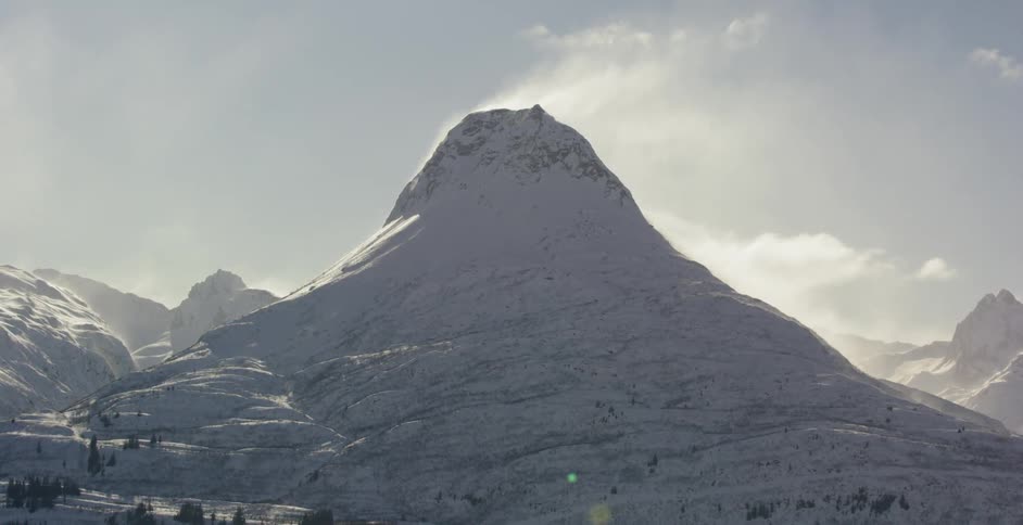 Wind blows over a snowy mountain peak