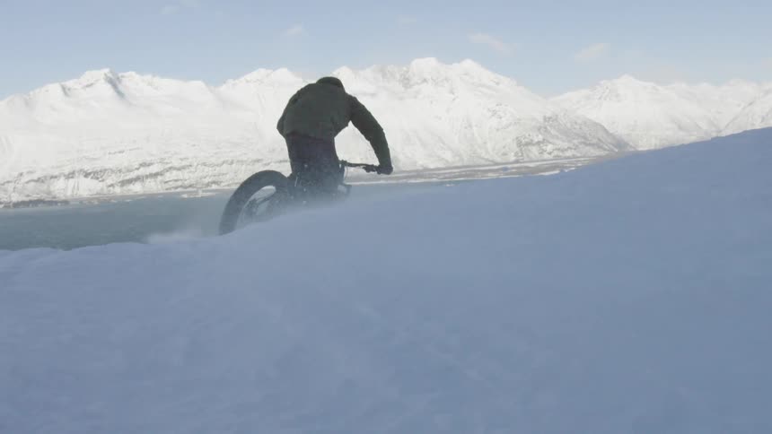 A bicyclist rides down a snowy hill
