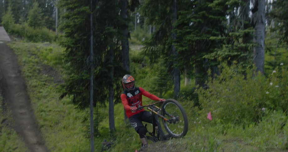 A person rides their mountain bike over a large hill jumping