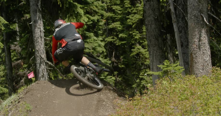 A bicyclist goes over a jump in a forest