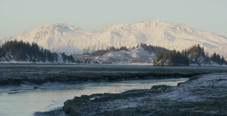 A river is flowing through a mountain valley in winter